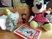Photo showing the oversized playing cards box, plush Minnie Mouse, and Dumbo plush.