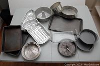 Overview of all bakeware items placed on table showing assortment including pans, molds and glass dish.