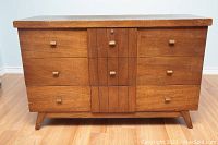Front view of mid century blanket chest showing wood veneer, brass knobs, and overall condition.