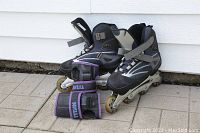 Pair of men's Ultra Wheels 'Axis Lite' inline rollerblades with front angle showing details including wheels and straps, positioned beside wrist guards.