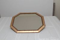 Top-down view of the octagonal gold framed mirror on white surface, showing overall shape and condition.