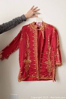Front view of red satin jacket showing gold embroidered details and long sleeves.