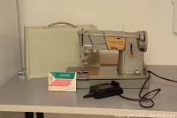 Full view of Singer Style-O-Matic 328 sewing machine with manual, foot pedal and carrying case on a table.