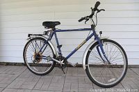 Full side view of the blue Specialized HardRock mountain bike showing overall frame, wheels, fenders and rear rack. Visible rust on rear hub.