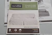 Front view of product packaging showing Sure-Fit branding, product details, and white matelassé damask slipcover image.
