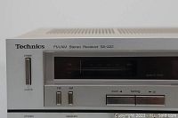 Close-up photo of the left side front panel showing power switch, FM and AM selector switches, tuning buttons, and tuning display with model and brand markings.