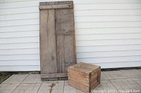 Photo of vintage wood panel and military wood box placed outside against white siding; shows panel height and box size.