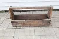 Angled view of vintage handmade wooden tool tote showing sturdy horizontal handle, wear and patina on wood surfaces