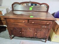 Front view of antique wooden dresser with attached mirror and two drawers on top, three doors below, mismatched and missing hardware visible.
