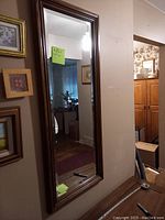 Full image of the bevelled wall mirror against a wall with surrounding picture frames visible