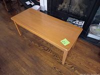 Full view of 1960s coffee table showing rectangular top and tapered legs on hardwood floor.