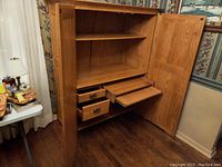 Open computer armoire showing interior shelves, drawers, and pull-out trays.