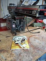 Close-up photo of Craftsman radial arm saw on workbench beside instruction book titled "Fine Tuning Your Radial Arm Saw".