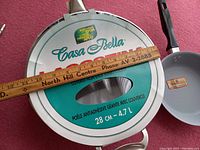 Close-up of the jumbo cooker lid showing brand Casa Bella and dimensions 28cm, 4.7L capacity.