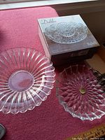 Photo showing three clear crystal serving bowls on a red surface near a window. One bowl remains in its original 'Dublin by Spiegelau' box, the others are out of the box showing their distinct ribbed and starburst patterns.