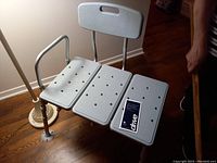 Full view of the gray medical bath transfer bench with perforated seat sections, backrest, and single armrest.