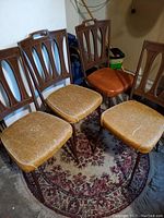 Photo showing six vintage chairs arranged closely on a carpet, highlighting seat cushions and chair back design.