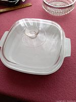 Top view of clear glass lid with handle and white ceramic skillet underneath