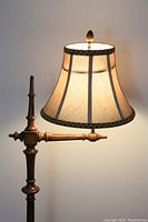 Close-up of the turned wooden stand and fabric lampshade with braided trim and top finial.