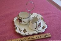 Cream and sugar set on tray, showing silver trim and handle with leaf pattern on porcelain pieces.