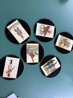 Top side view of six round black-bordered placemats featuring vintage British military regiment illustrations