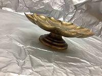 Side view of the small brass plant stand showing the round top and the layered stepped pedestal base.