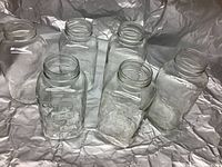 Seven large clear glass mason jars shown, embossed with the word Mason, with wide mouths for liquid canning and storage.