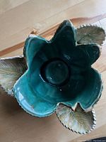 Top-down view showing the flower petal shape and teal glossy interior with sculpted leaf accents around the rim.