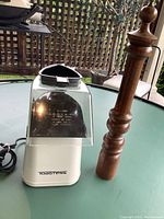 Popcorn maker and wooden grinder side by side on a glass table outdoors