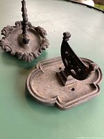 First photo showing both cast iron boot scrapers laid on green surface, highlighting the size, base shape and vertical scraper plates.