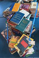 Top view of a large pile of assorted books including medical textbooks and cookbooks with varied colors and sizes.