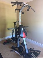 Full view of Bowflex home gym with multiple resistance rods, padded seat and backrest, lat pulldown bar and resistance cables.