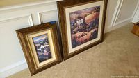 Two framed Tuscany-themed wallhangings resting against a wall on carpet, showing size and frame details.