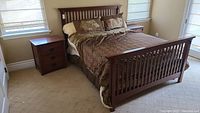 Wide shot of the queen bed, two night stands, and partial view of one night stand drawer