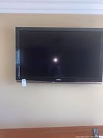 Front view of the 52 inch Sharp flat-screen television mounted on a wall showing the full screen and logo.