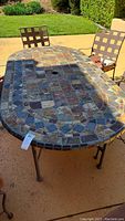Top and side view of outdoor patio table with multi-colored tile top and metal frame with two matching chairs.
