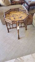 Side view of octagonal wooden end table showing bamboo-style legs and frame, carpet background