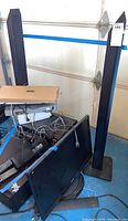 View of the lot containing two tall black speakers, a ViewSonic television lying face down, stereo receivers, and other electronic devices piled together with cables visible.
