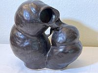 Front angle view showing the overall shape, size, and dual spout openings of the dark brown glazed pottery sculpture.