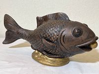 Side view of ceramic carp sculpture showing details of scales, fins, and mouth with gold ball.