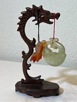 Overall photo of carved black Heizhi dragon stand with two pendants hanging from dragon's mouth.