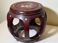 Full view of the round rosewood garden seat showing dark red polished wood with open arch design around the legs.