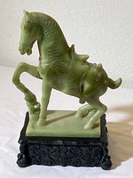 Full side view of green faux jade horse sculpture on black base
