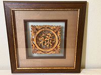 Framed Chinese wood carving with beige matting and gold inner trim, showing entire frame front