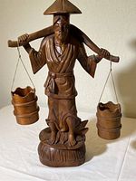 Full view of the carved wooden statue portraying a Japanese man with a yoke and two buckets, standing 22 inches tall.