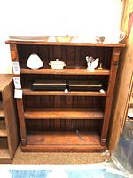 Front view of wood bookcase with various small decorative items on the shelves.