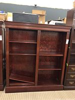 Front view of wooden bookcase showing both shelving sections and carved top trim.