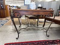 Side view showing wood top and metal legs with scrollwork design