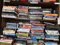 Top view of DVDs stacked horizontally and vertically showing a mix of genres including musicals, children's films, and classics.
