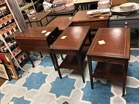 Photo showing three wood end tables including two matching tables with drawers and a drop leaf table.